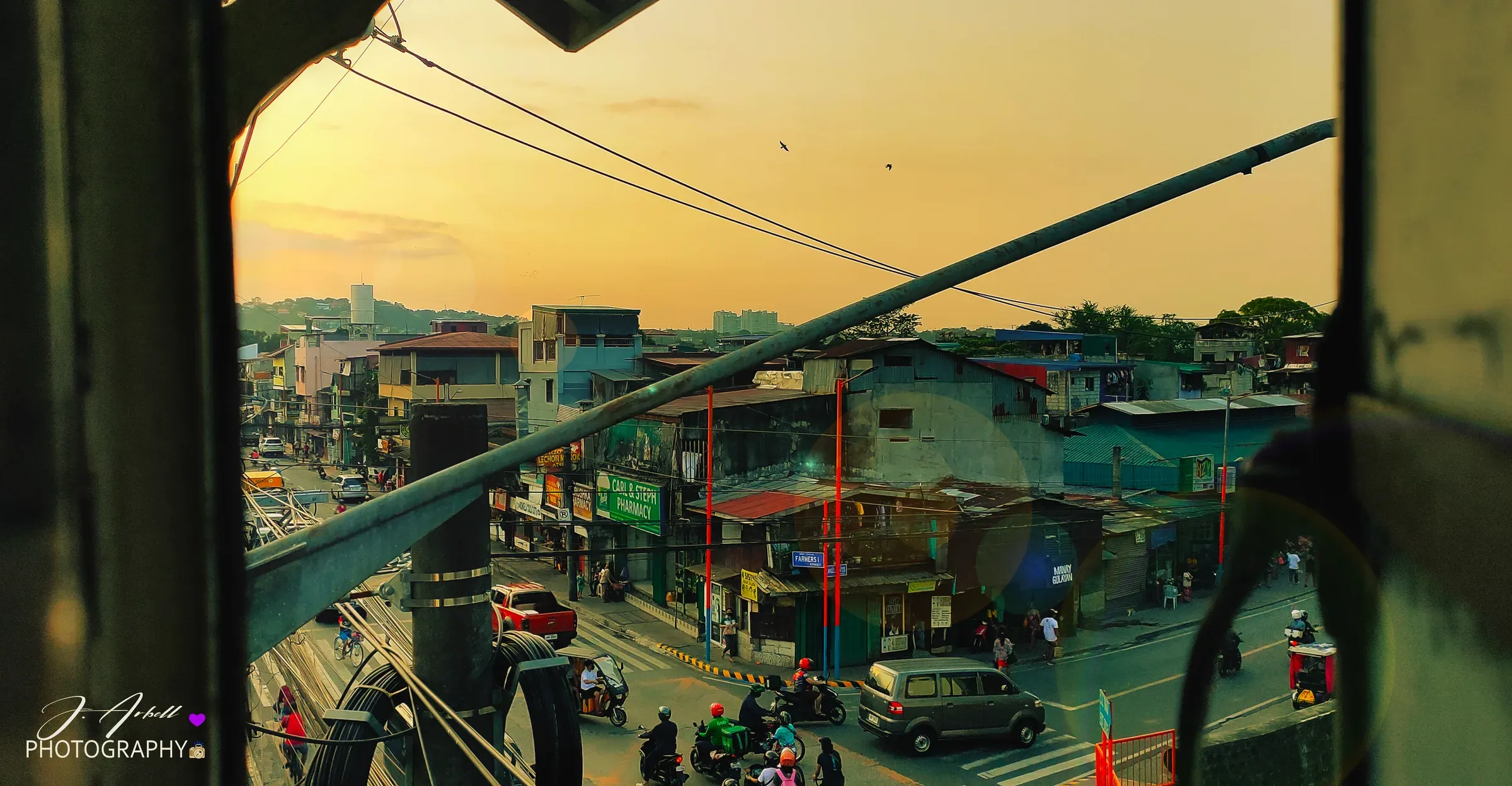 A Marikina street at golden hour seen through the open side of a moving jeepney
